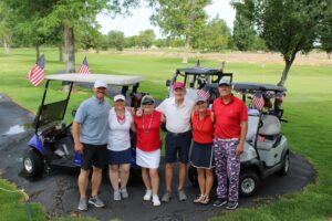 Golfers pose on the cart path with their carts at the Russ Hansen Memorial Scramble.